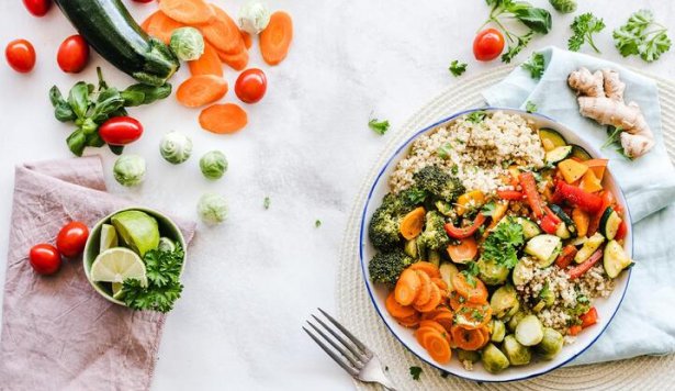 A bowl of fresh, healthy food is presented. Surrounding the bowl are additional ingredients placed on a table.