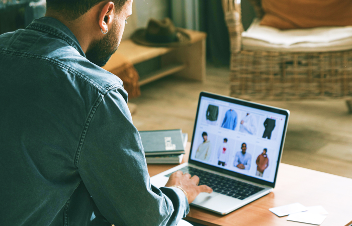 A person browsing an online clothing store on a laptop, with various shirts displayed on the screen.
