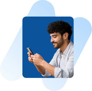 A man is smiling while looking at his phone.